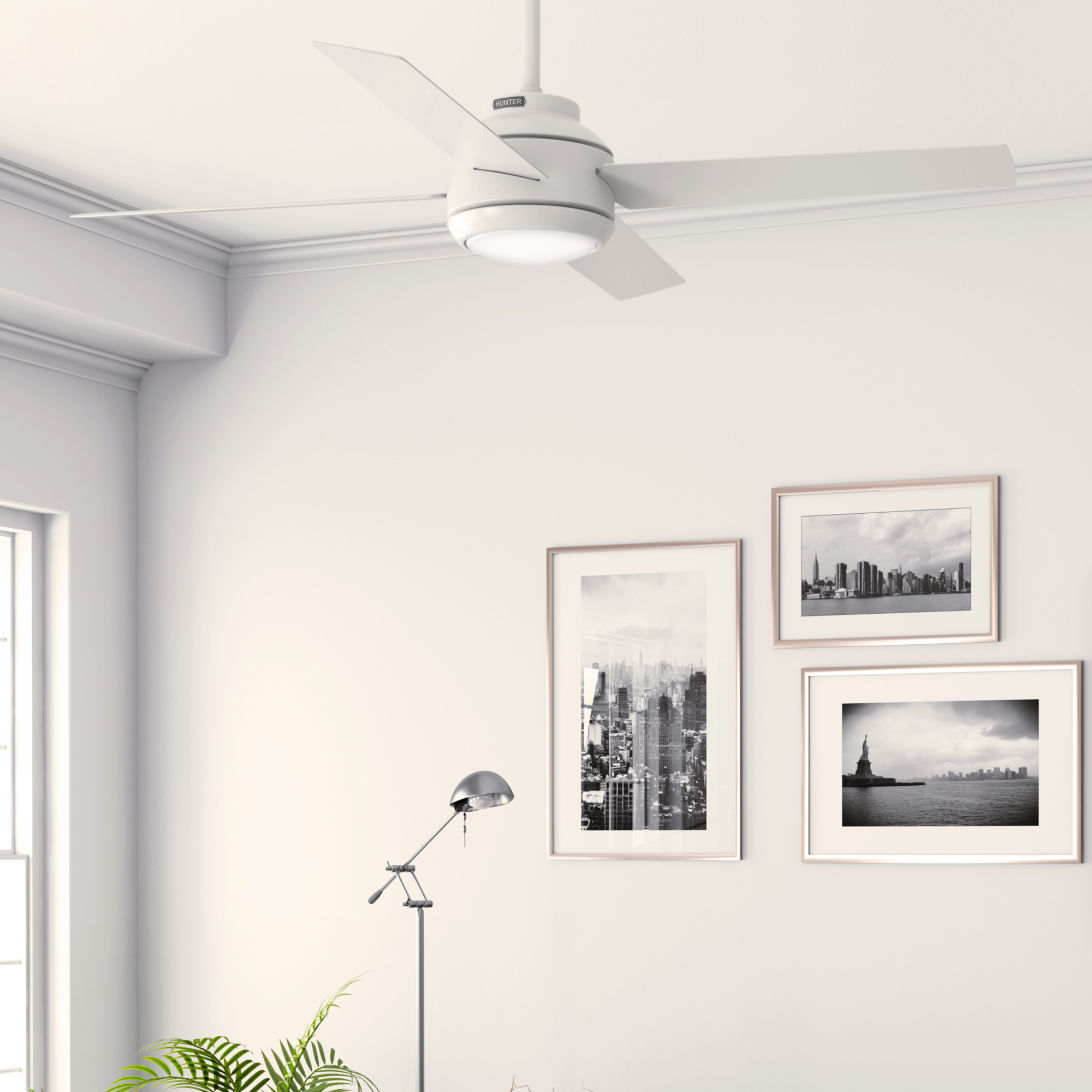 Ein Zimmer mit weißem Deckenventilator, drei gerahmten Bildern und einer Stehlampe.