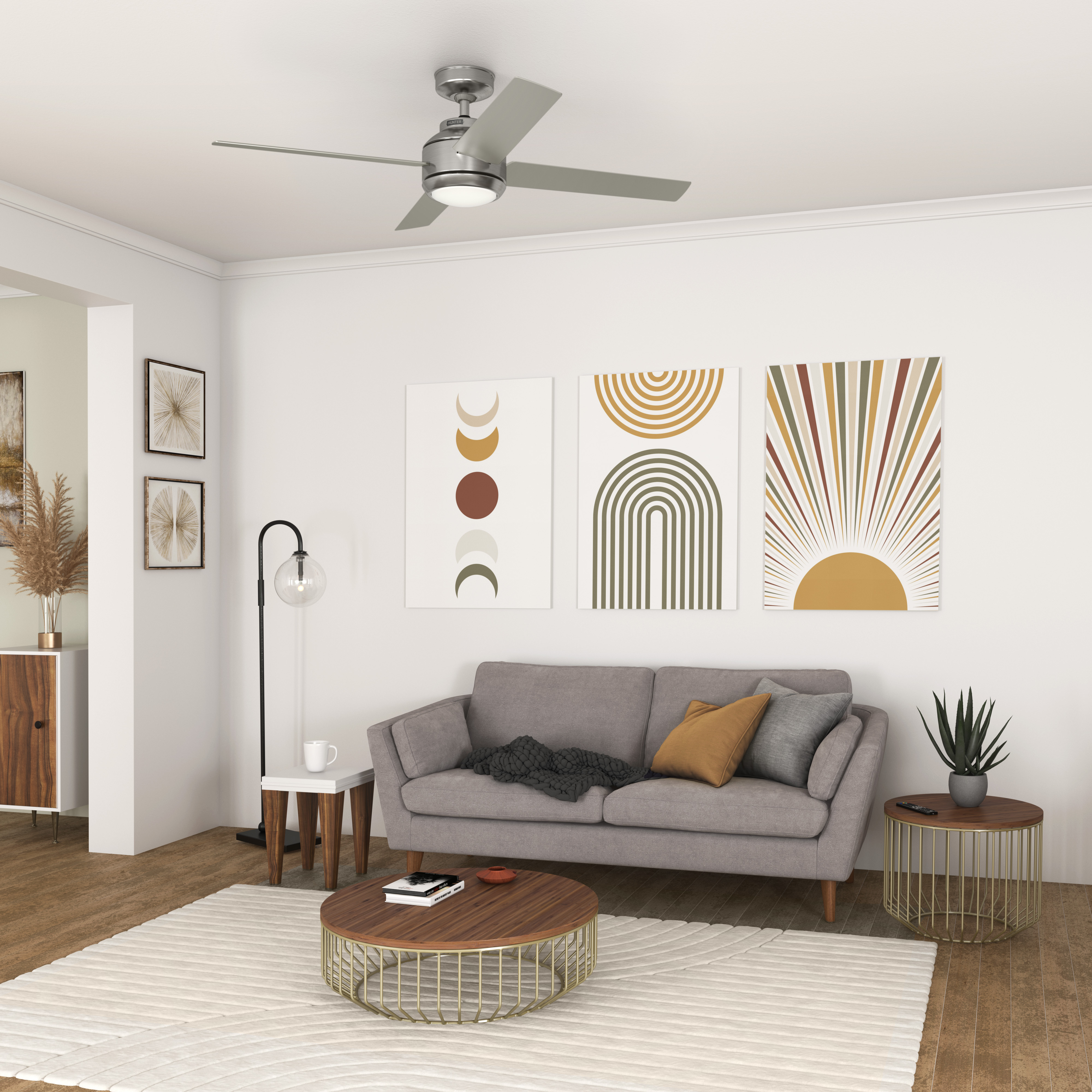 Wohnzimmer mit grauem Sofa, rundem Couchtisch, Kunst und silbernem Deckenventilator.