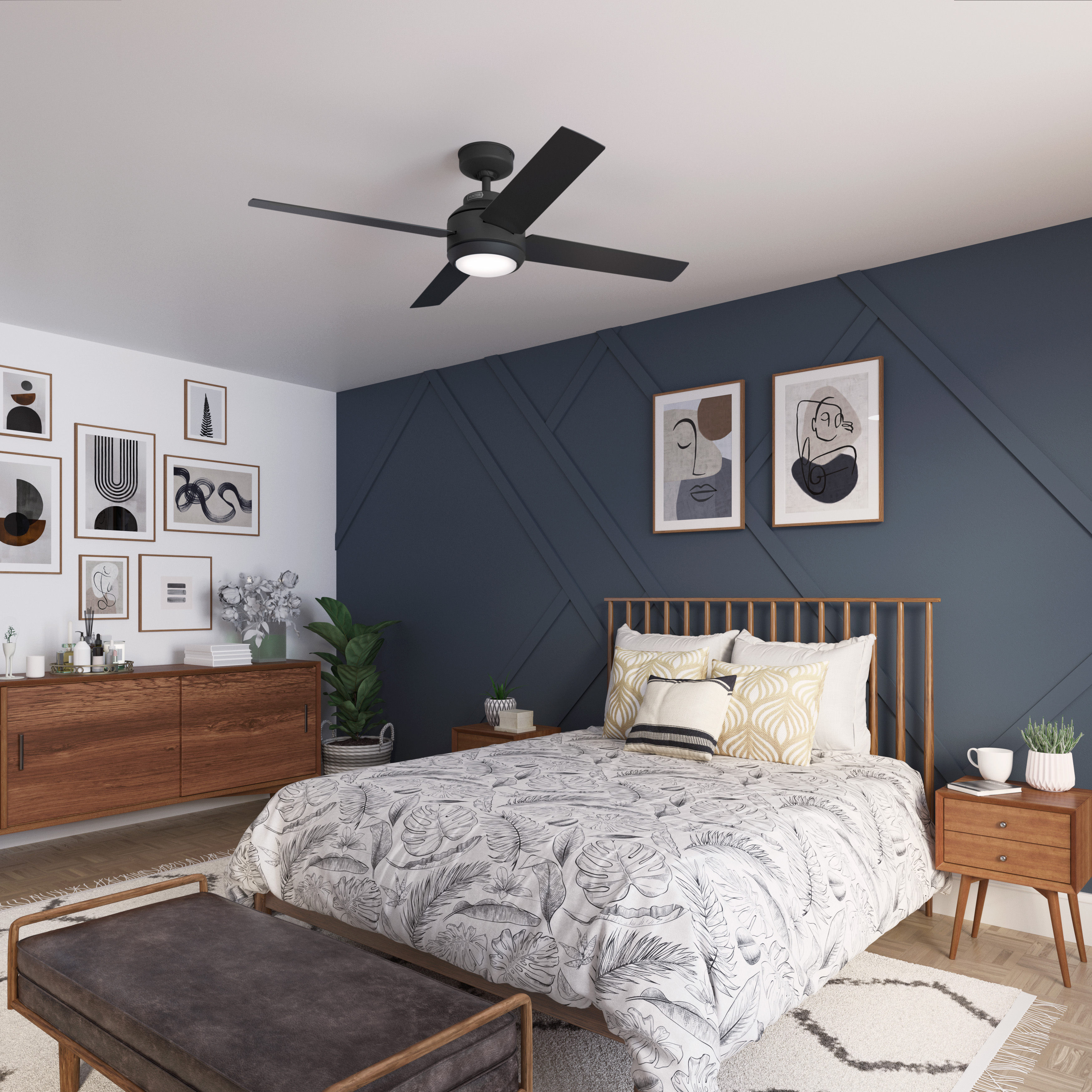 Schlafzimmer mit dunkelblauer Akzentwand, Kunst, Holzmöbeln, Deckenventilator und Bett mit gemusterter Bettwäsche.
