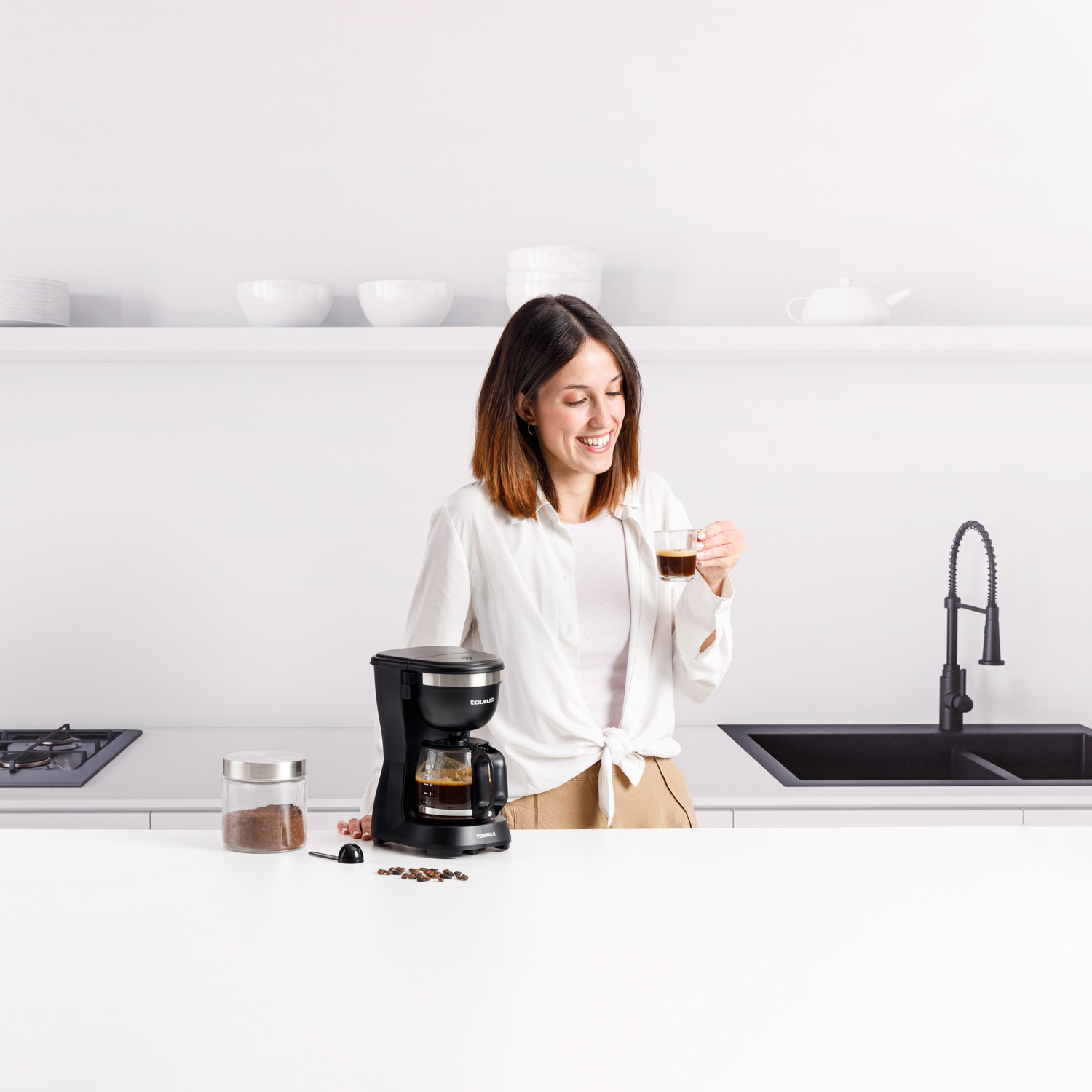 Zbliżenie czarnego ekspresu do kawy ze szklanym dzbankiem, pokazujące wskaźnik poziomu wody.