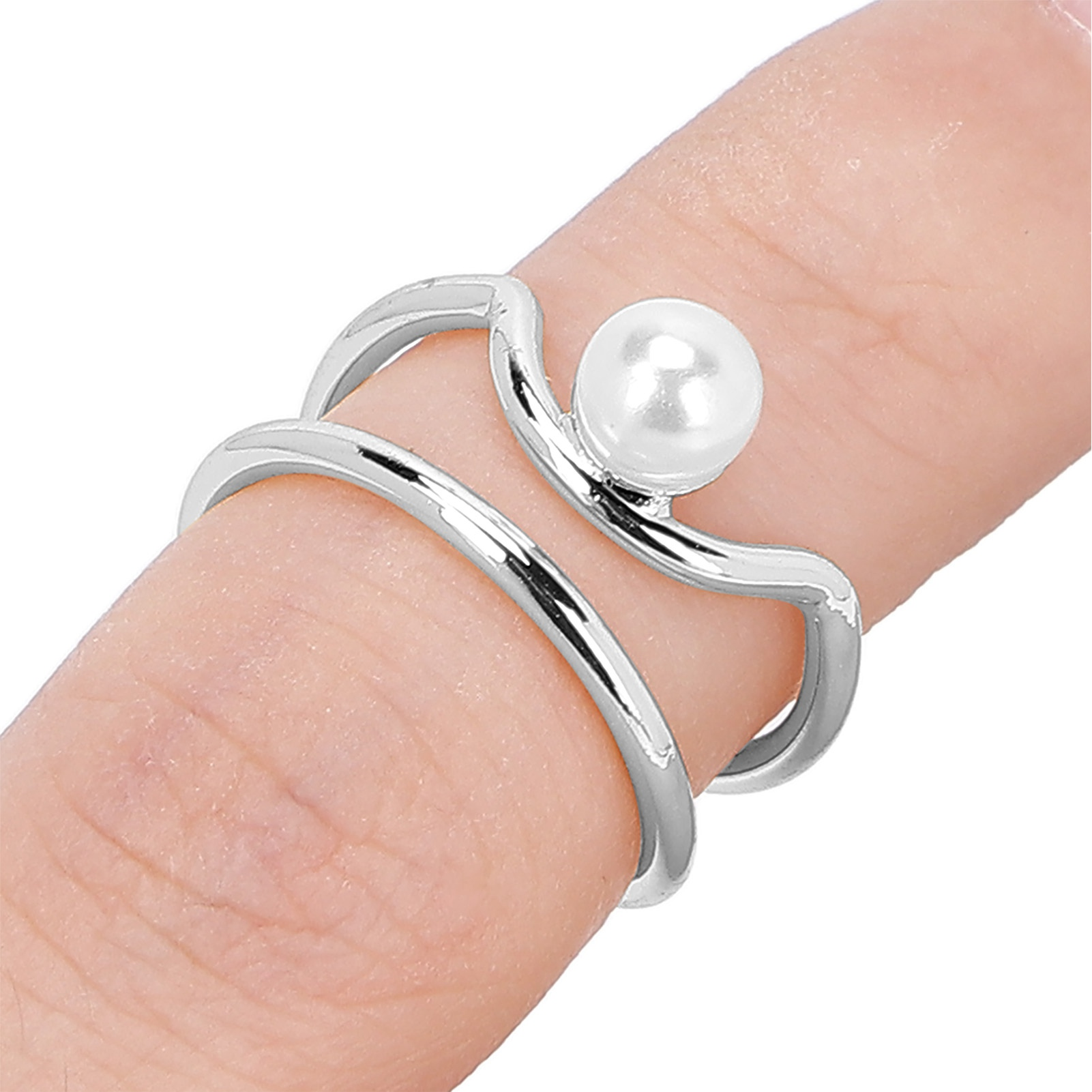 Ein Ring an einem Finger, mit silbernem Band und einer weißen Perle. Das Doppelschlaufendesign des Rings ist sichtbar.