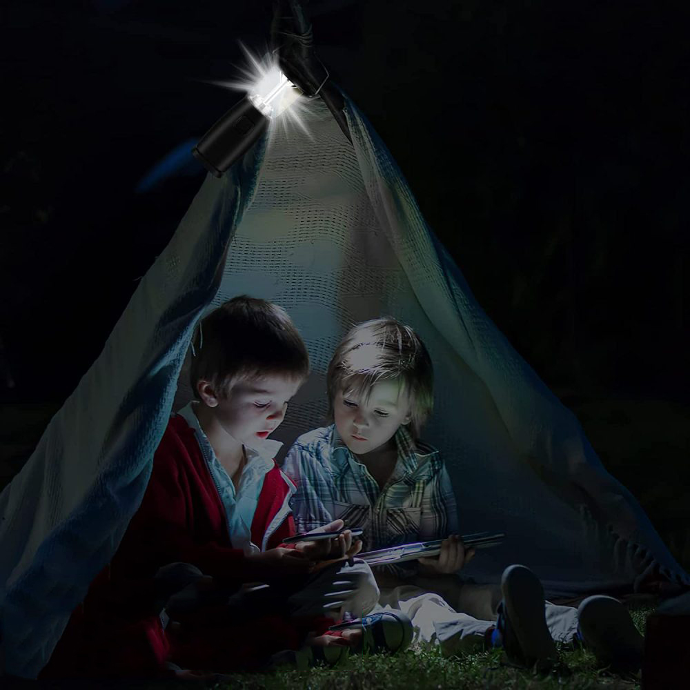 Zwei Kinder lesen unter einem Zelt, das von einer Taschenlampe beleuchtet wird.
