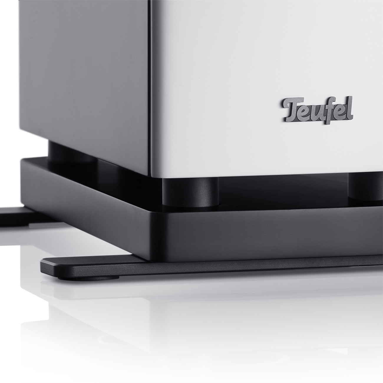 Nahaufnahme des Lautsprechersockels mit dem Teufel-Logo auf weißem Hintergrund.