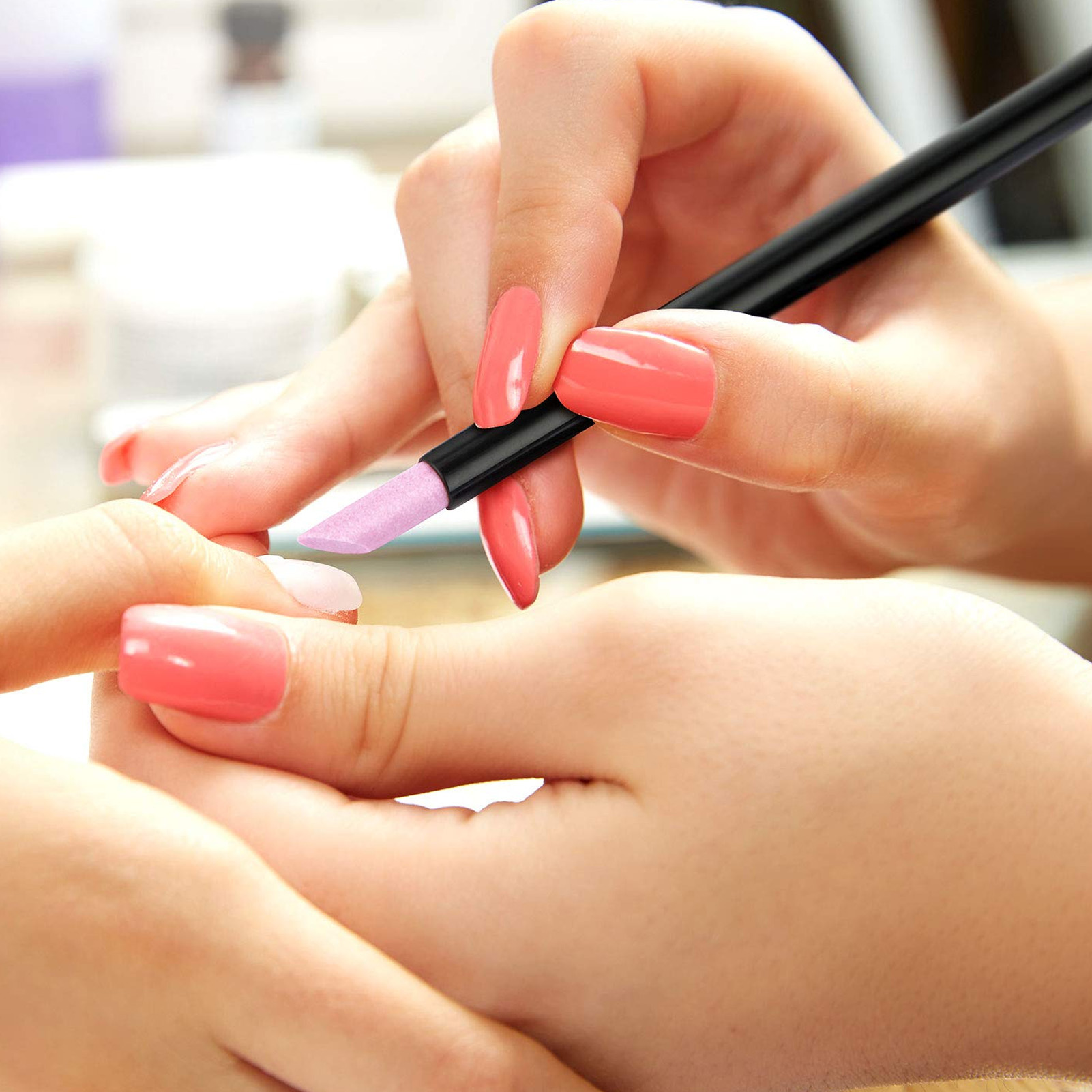 Hände einer Person, die Nägel mit rosa Nagellack lackiert.
