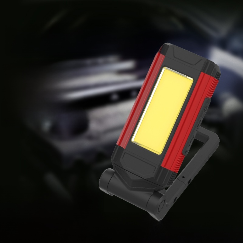 Ein rotes und schwarzes LED-Arbeitslicht ist geneigt. Es befindet sich auf schwarzem Hintergrund.