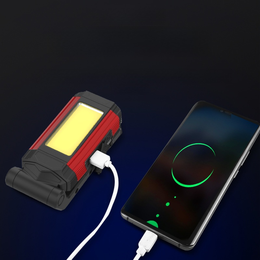 Eine rot-schwarze Taschenlampe lädt ein Smartphone mit einem weißen Ladekabel auf.