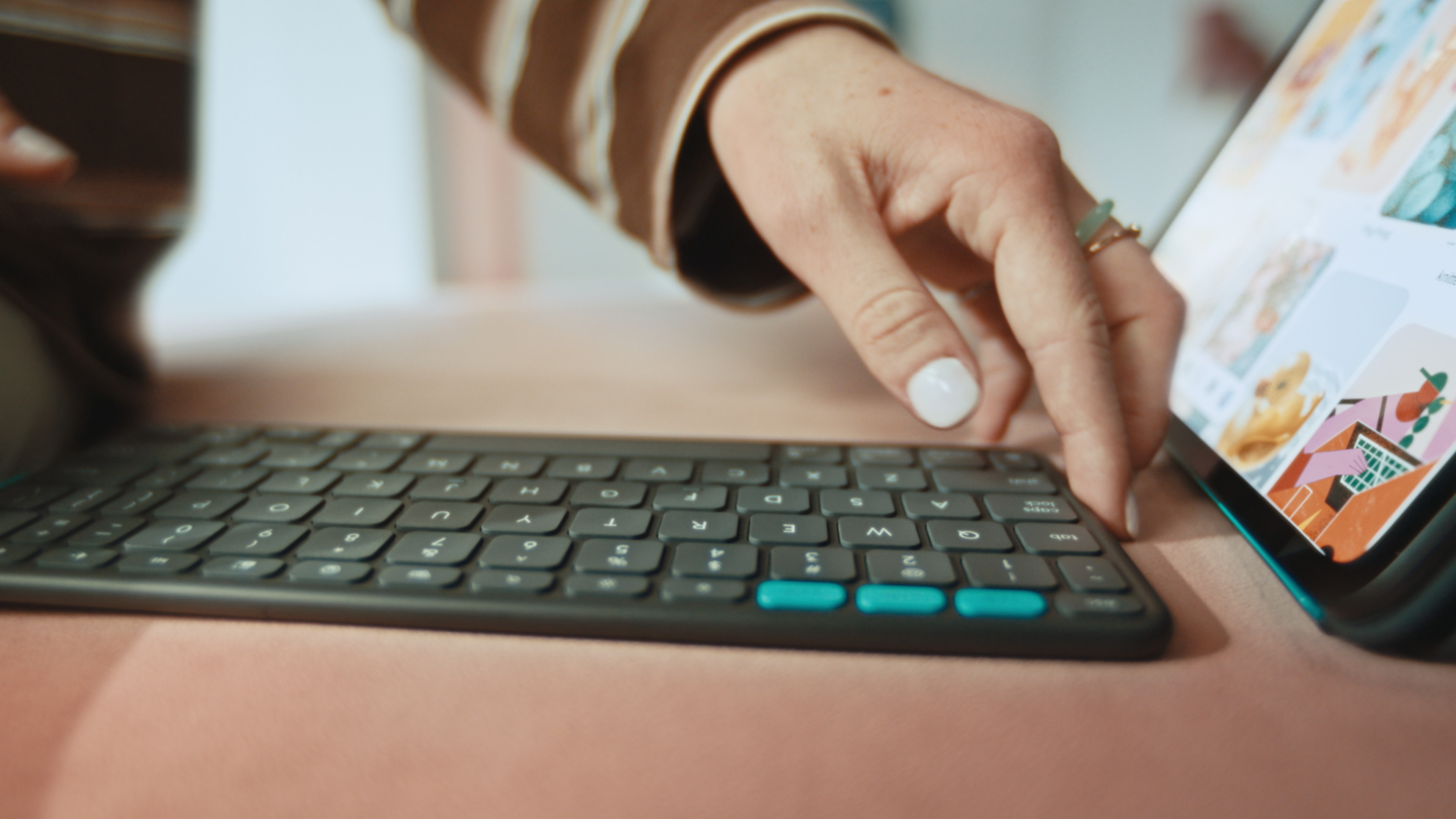 La mano di una persona è vicino a un tablet e una tastiera.
