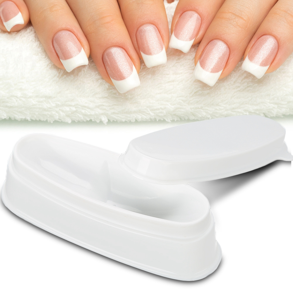 Ein Nagelkunstwerkzeug und eine Hand mit französisch manikürten Nägeln. Das Werkzeug ist weiß und oval.