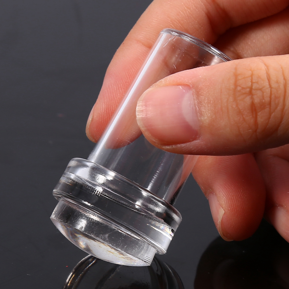 Eine Hand, die einen transparenten, zylindrischen Behälter mit leicht gebogener Basis hält.
