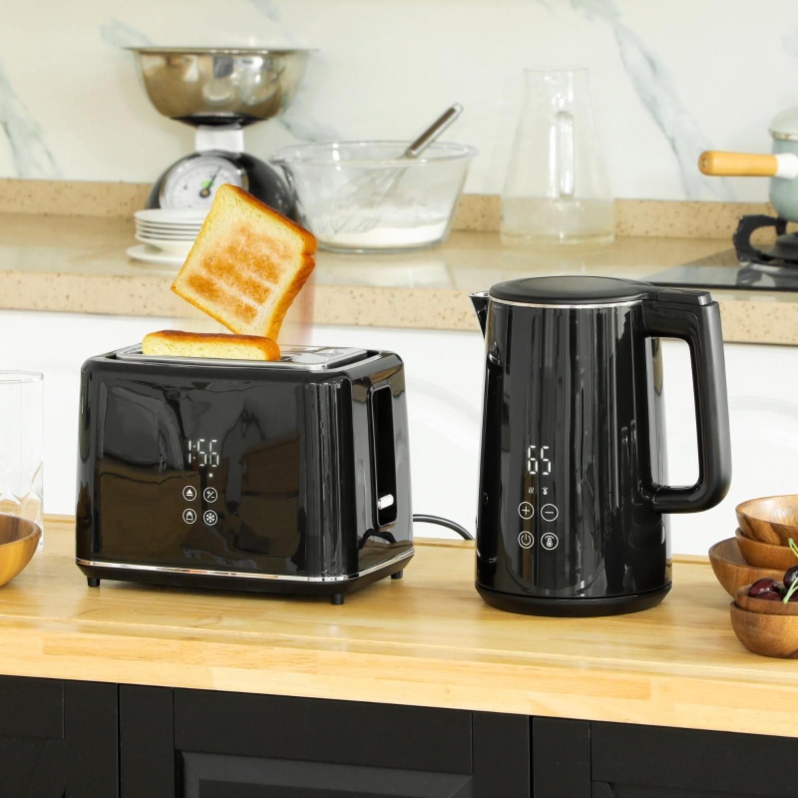 Ein schwarzer Toaster mit herausspringendem Toast und ein schwarzer Wasserkocher. Beide stehen auf einer Holztheke.