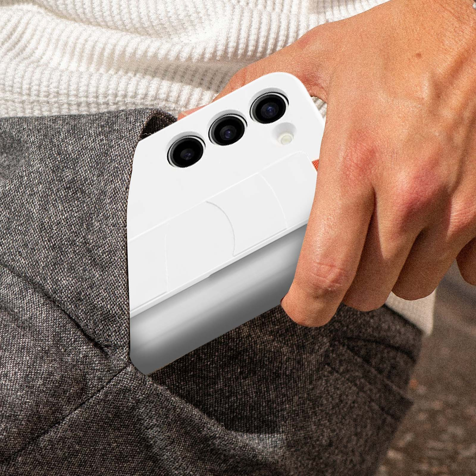 Een hand die een witte telefoon in een witte hoes vasthoudt, gedeeltelijk in een zak. De telefoon heeft drie camera's.