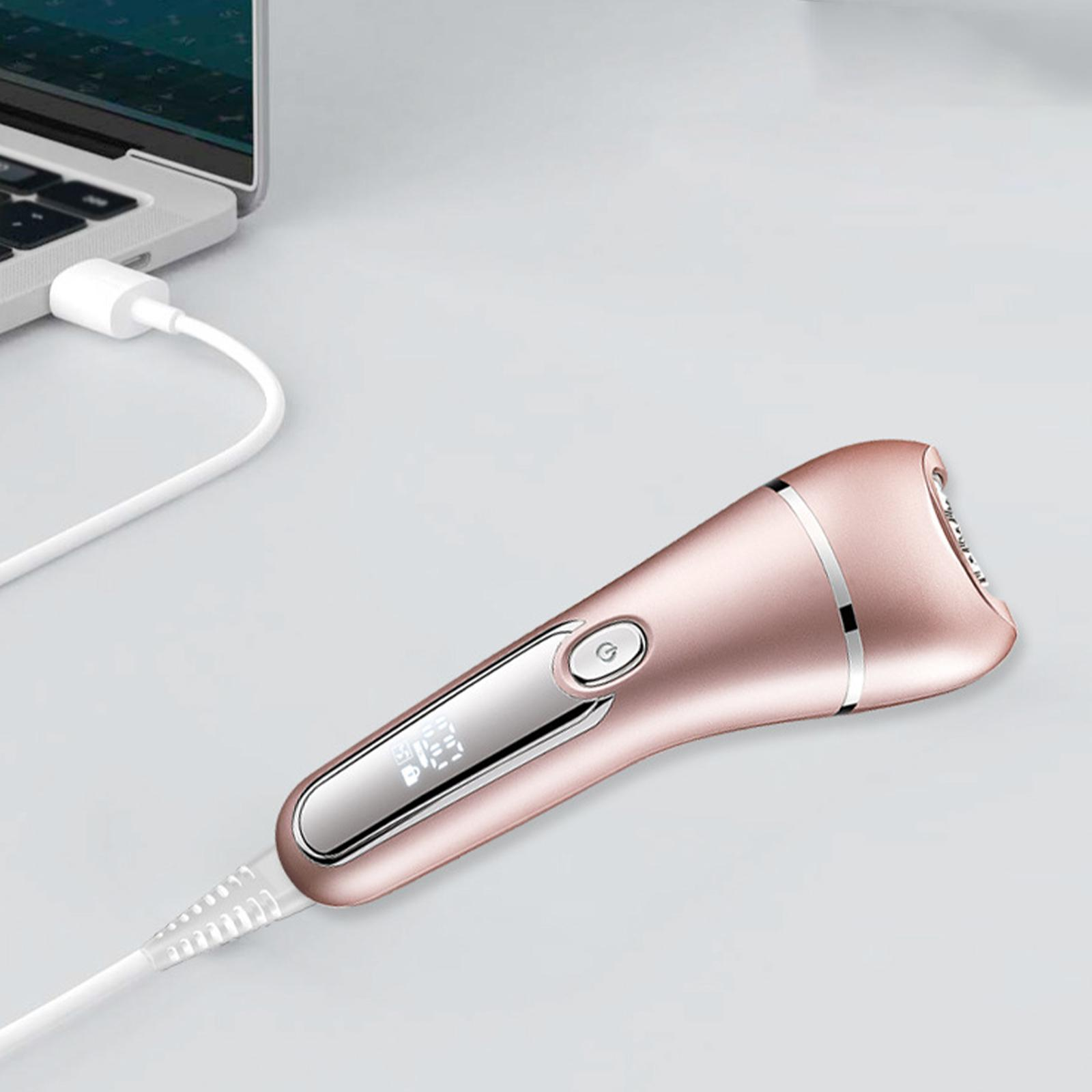 Ein roségoldener Elektrorasierer, der mit einem weißen Kabel an einen Laptop angeschlossen ist.