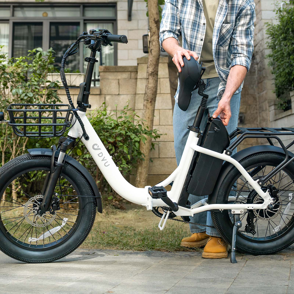 Osoba mocuje czarny akumulator do białego roweru. Tło to zielona trawa.