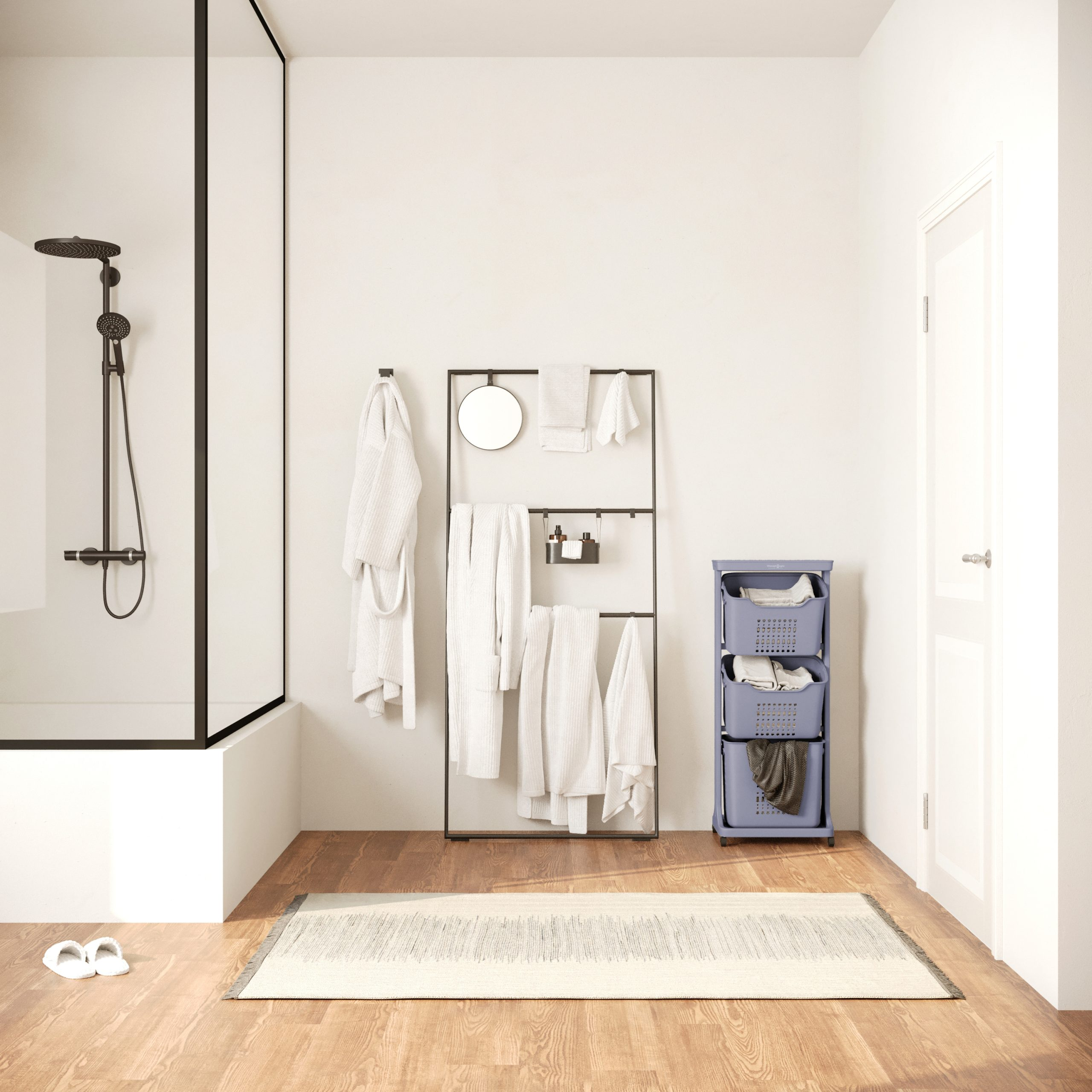 Een badkamer met een douche, handdoeken en een wasmandwagen. Een tapijt en een gesloten deur zijn zichtbaar.