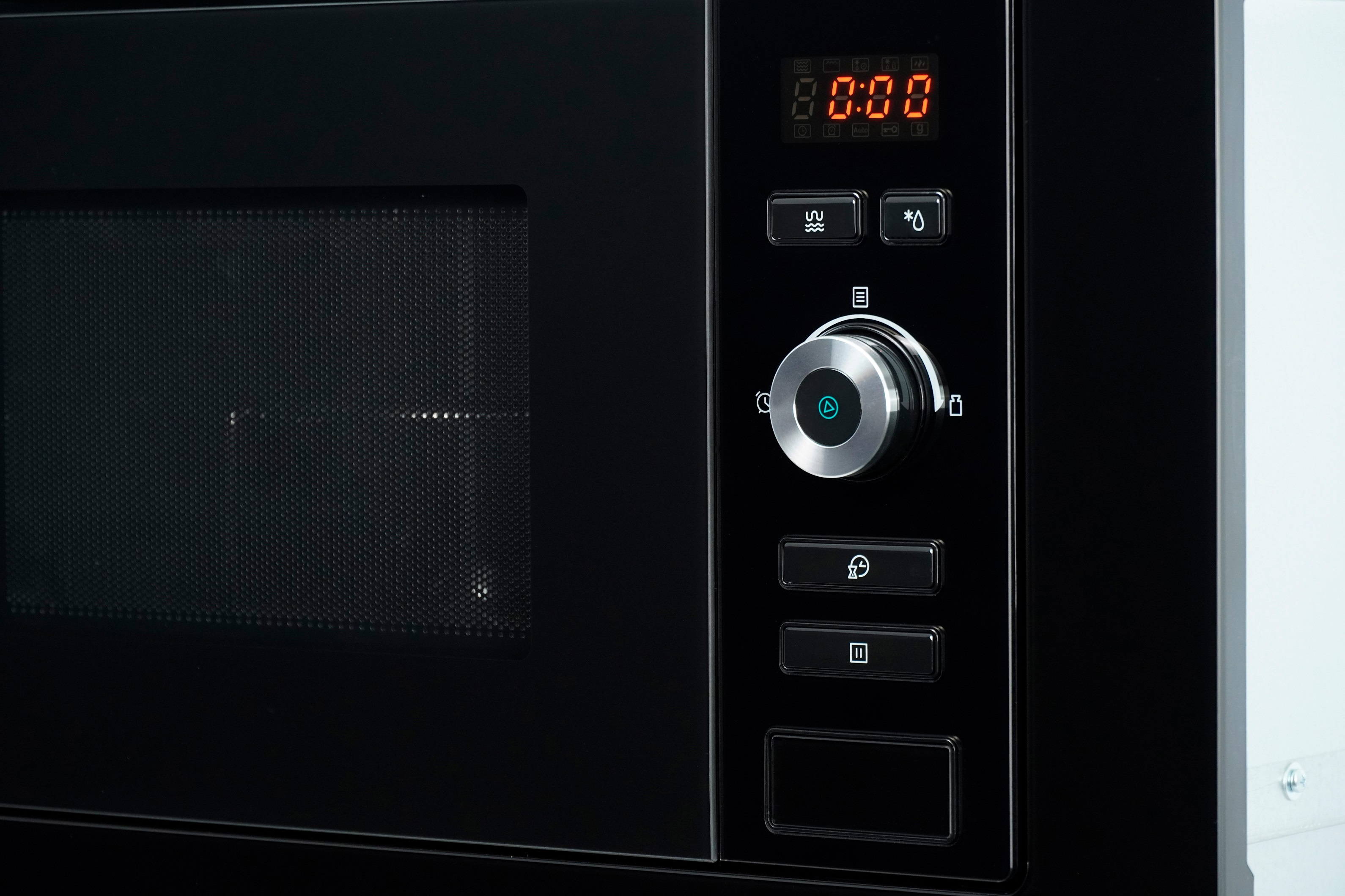 Close-up of a black microwave control panel with a digital display and various buttons.