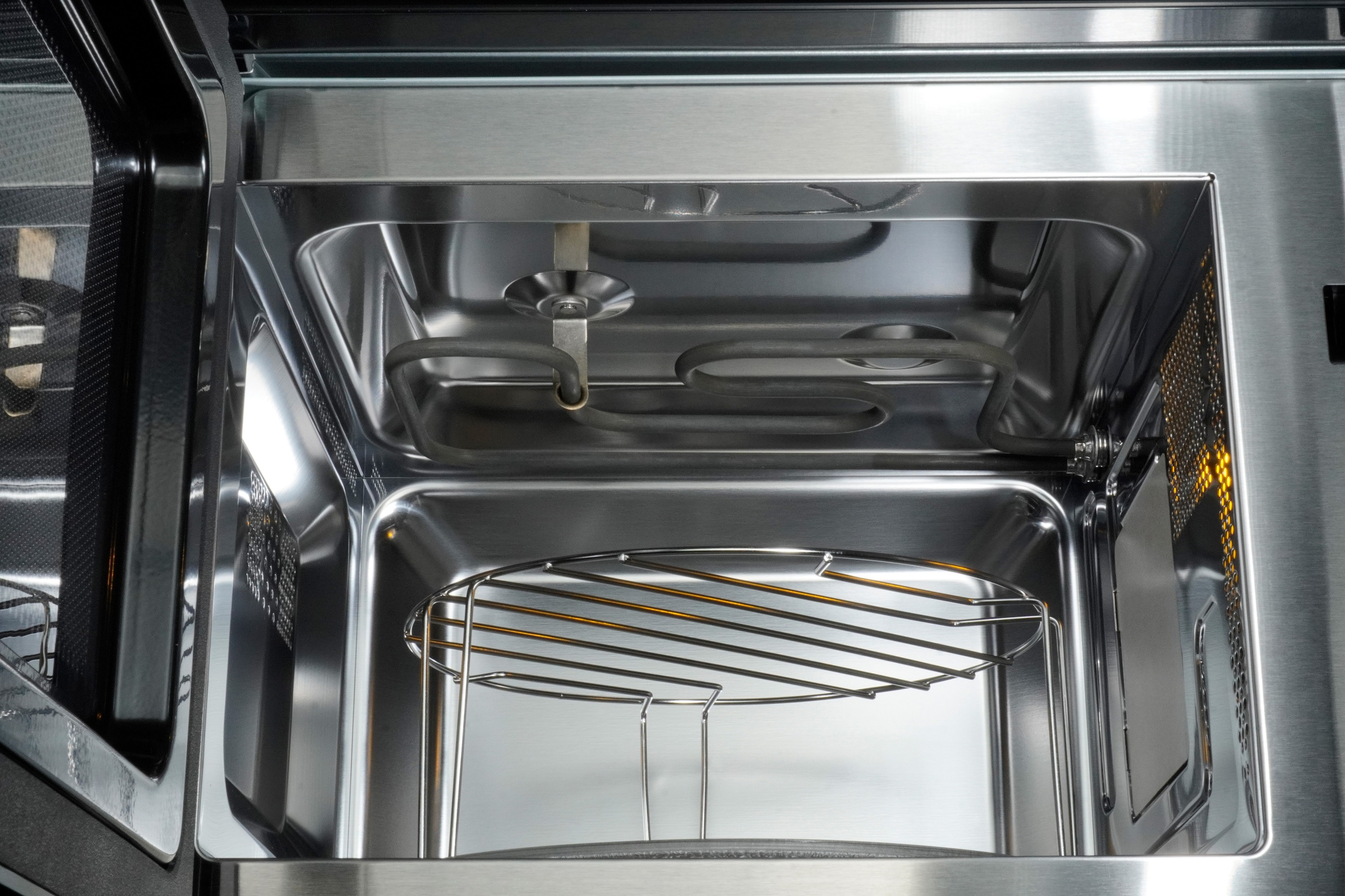 Interior of a microwave oven. Metal rack and heating elements visible.