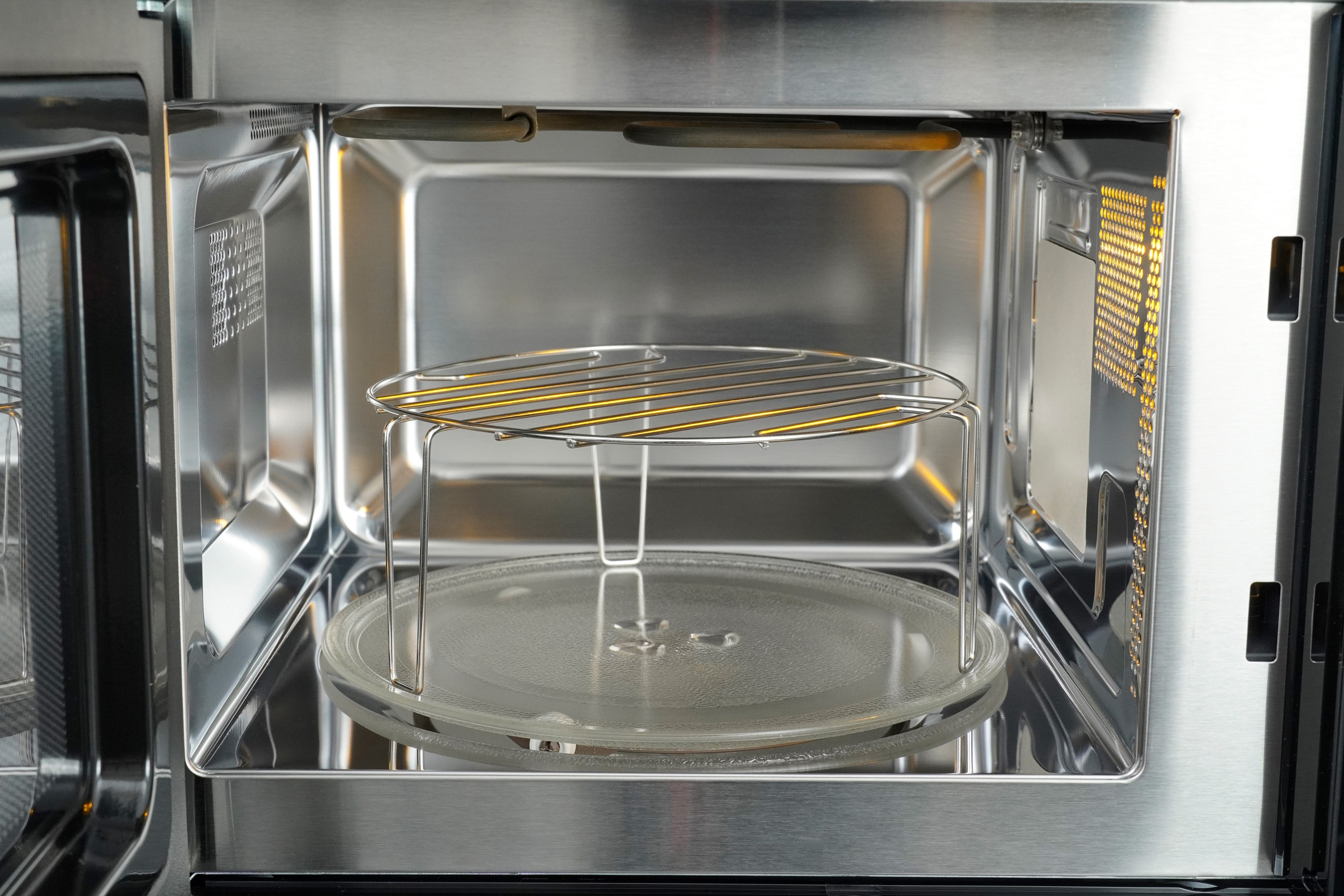 Interior of a microwave oven with a glass turntable and a metal rack inside.