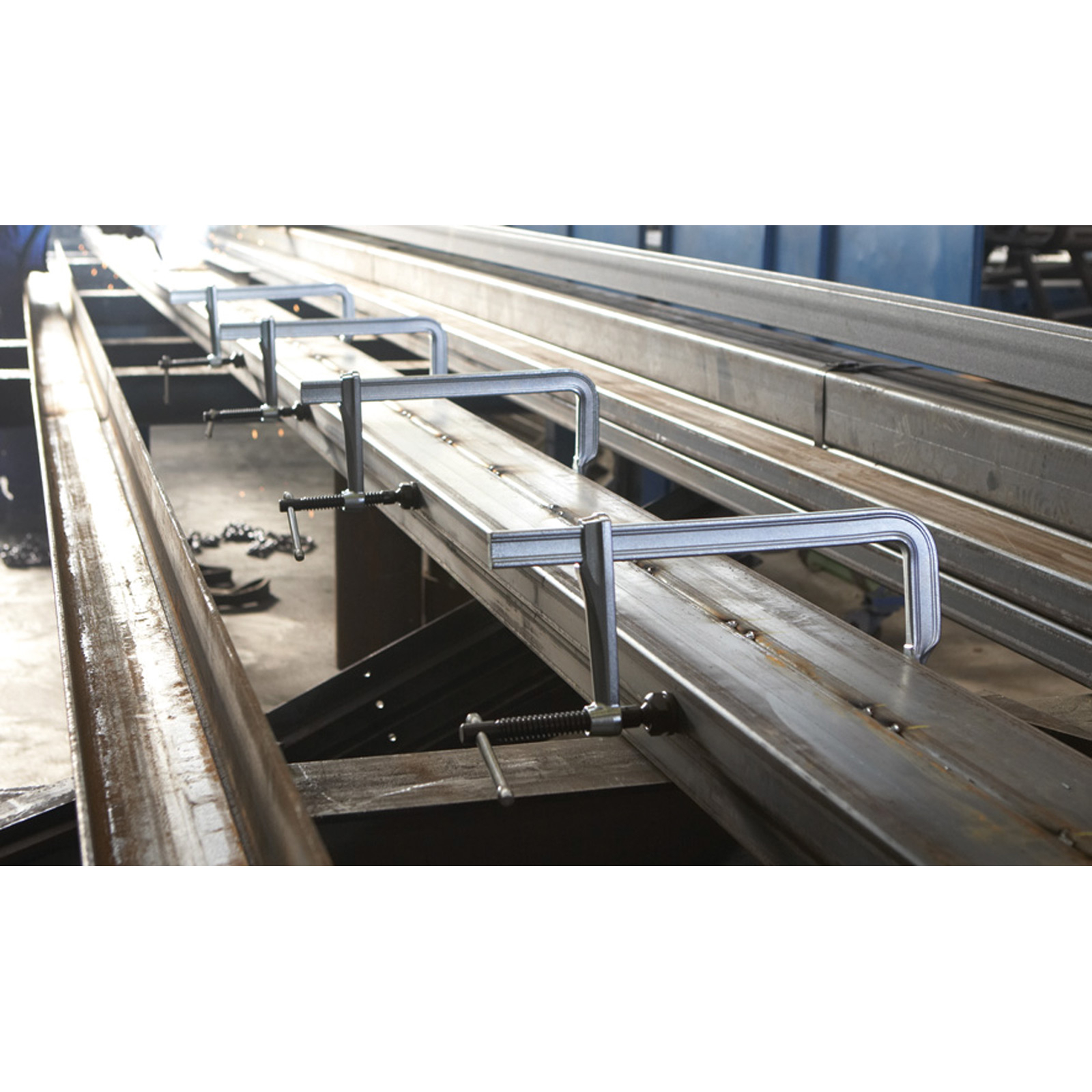 Metallklemmen, die Metallträger zusammenhalten. Die Träger befinden sich in einer Fabrikumgebung.