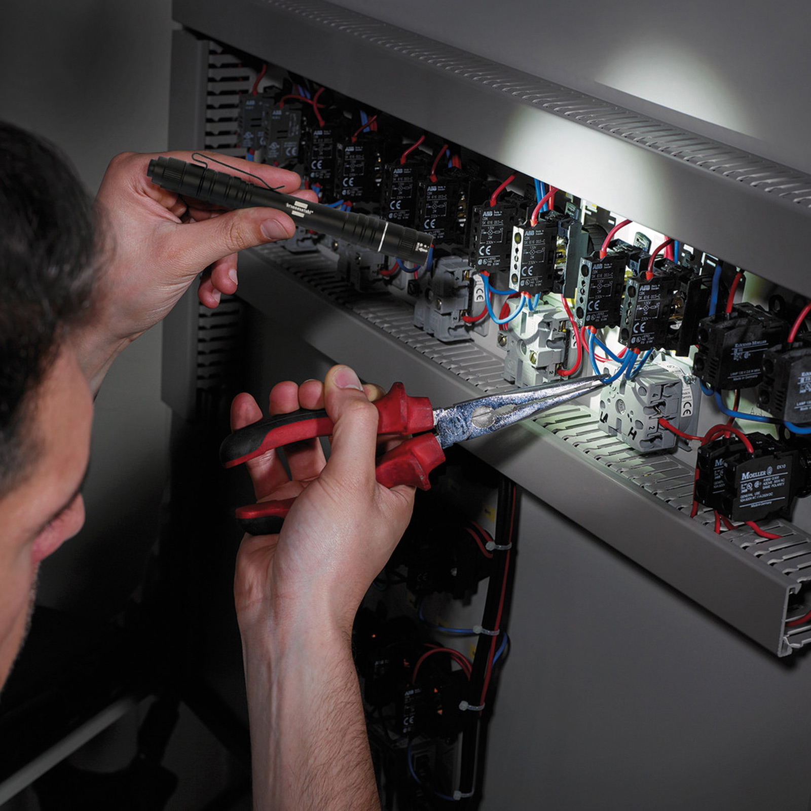 Una persona usa degli strumenti per lavorare su componenti elettrici in un pannello.