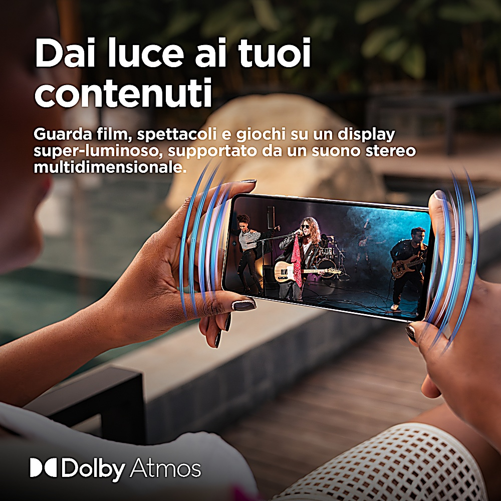 Hände halten ein Smartphone, das eine Band bei einem Auftritt zeigt, mit Dolby Atmos-Branding am unteren Rand.