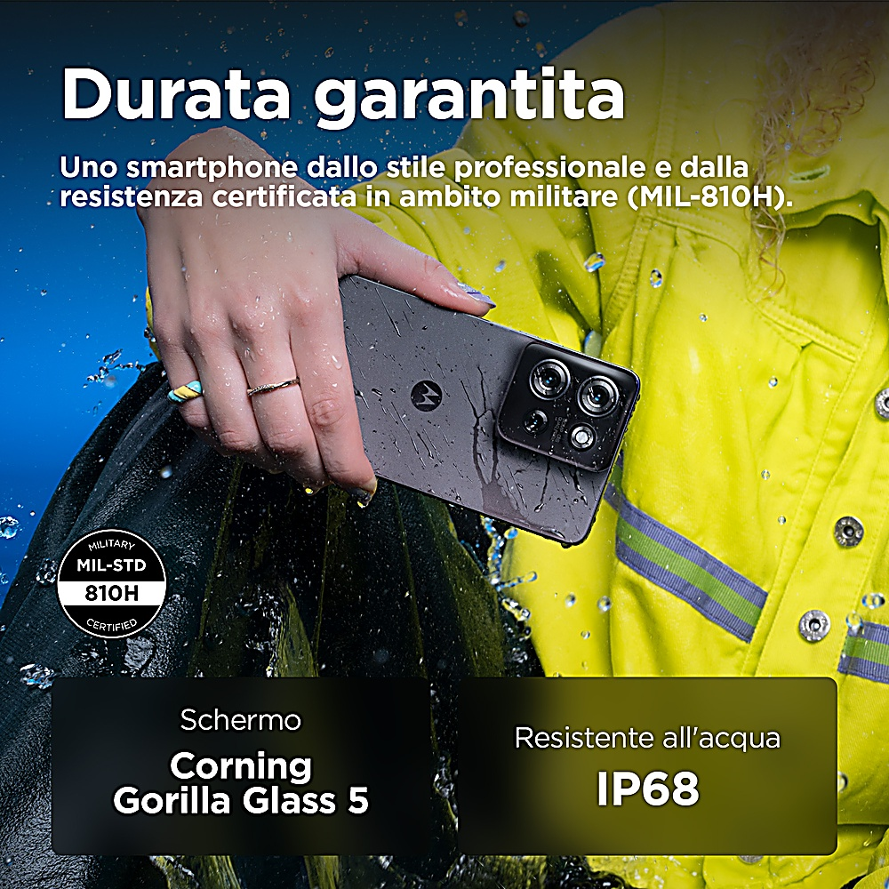Una persona tiene in mano un telefono Motorola nero. Testo in italiano, una giacca gialla e varie etichette sono visibili.