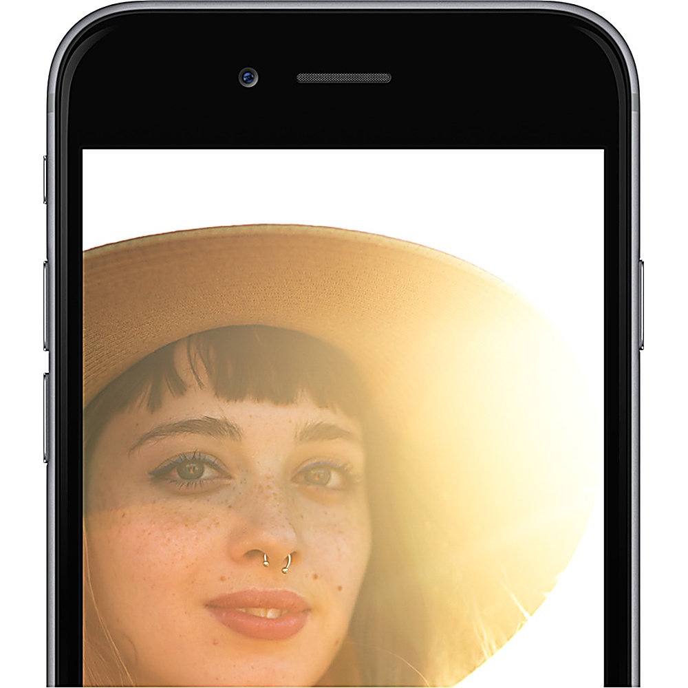 Una donna con un cappello è vista in un telefono. Ha un piercing al naso e lentiggini. Lo sfondo è luminoso.