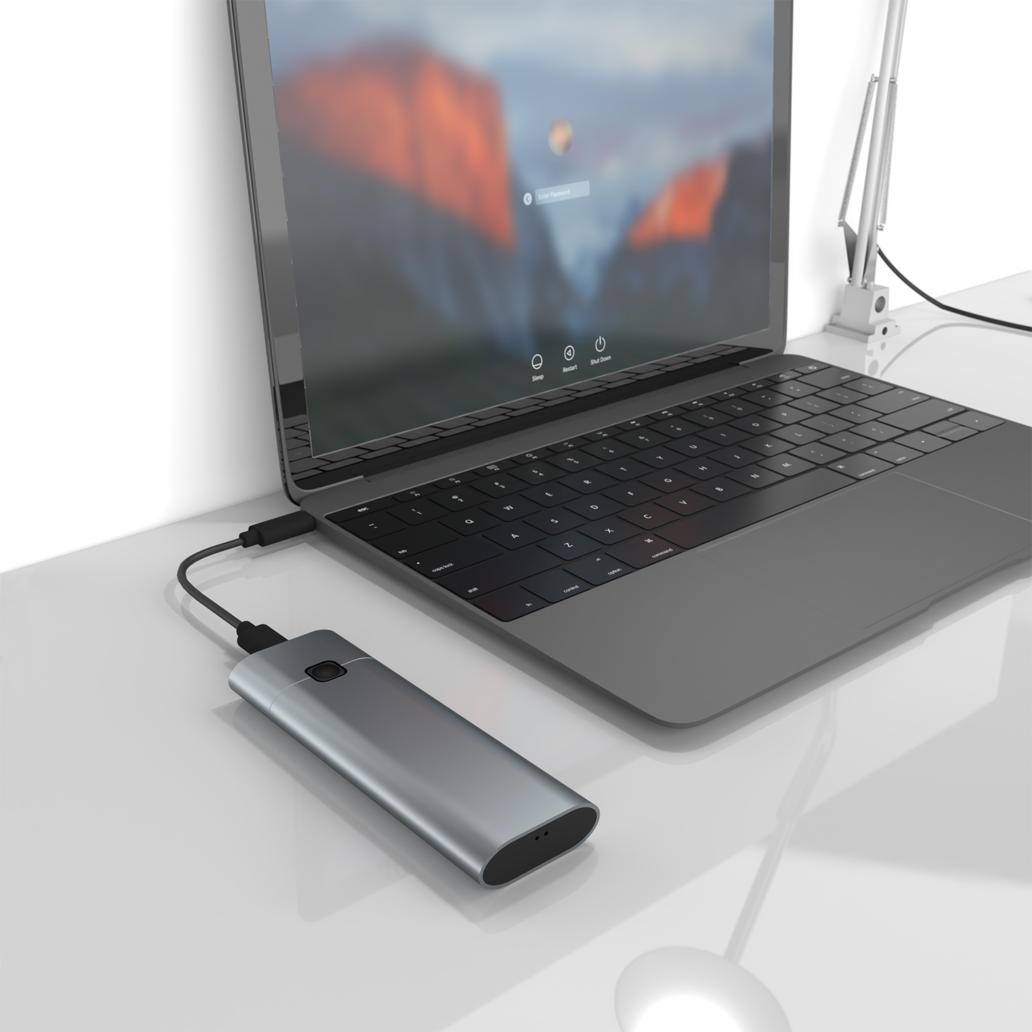 Dispositivo argento collegato a un laptop con cavo USB, su scrivania bianca.