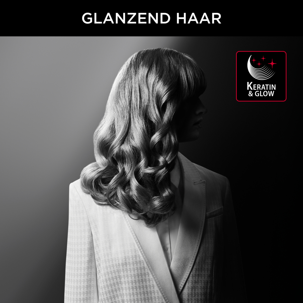 Kobieta z falowanymi włosami, w białym garniturze, na ciemnym tle z logo Keratin & Glow.