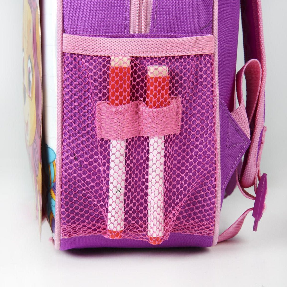 Una mochila morada con un bolsillo de malla que contiene dos marcadores rojos y blancos. Un cuaderno es visible en el fondo.