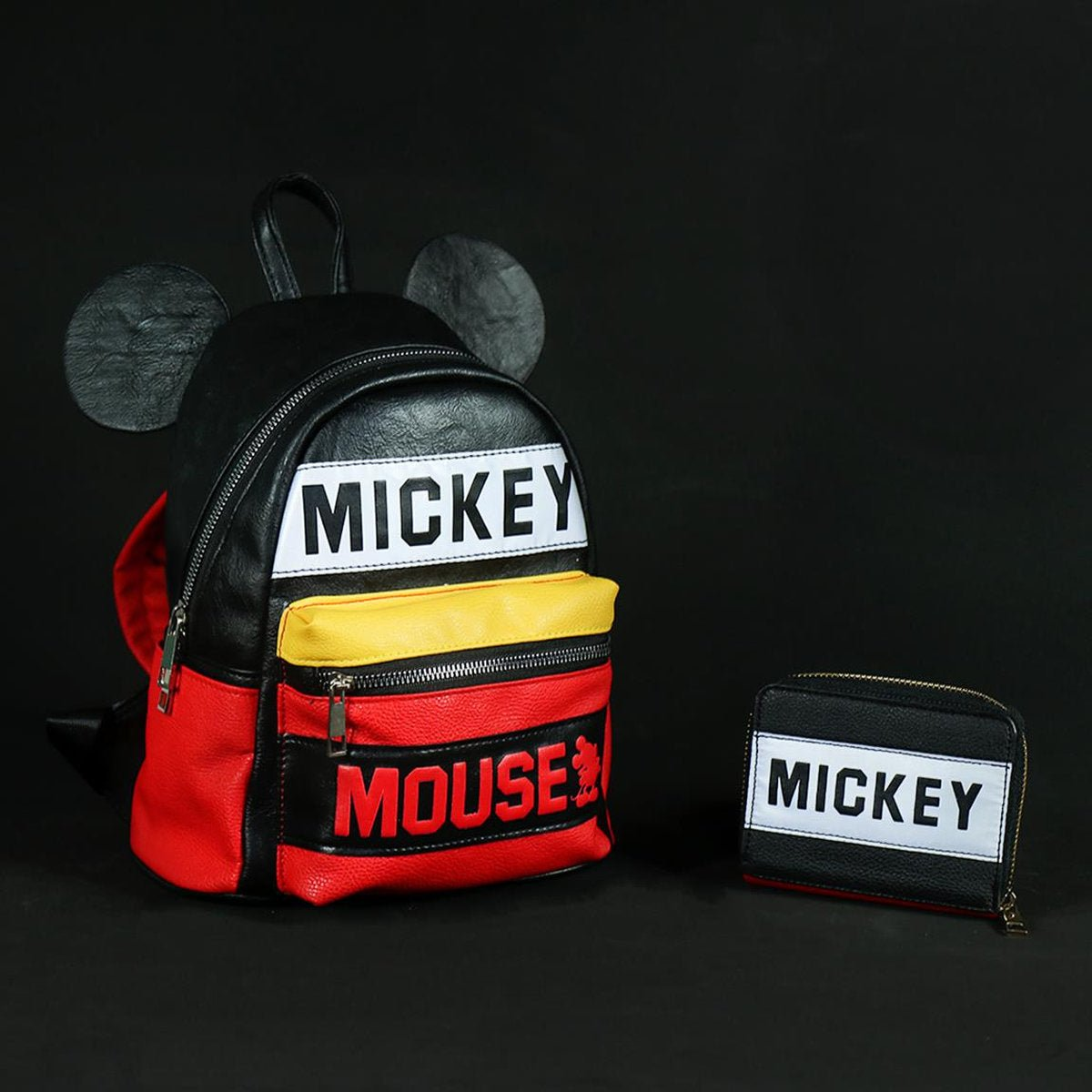 Mochila de Mickey Mouse negra y roja con cartera sobre fondo negro.