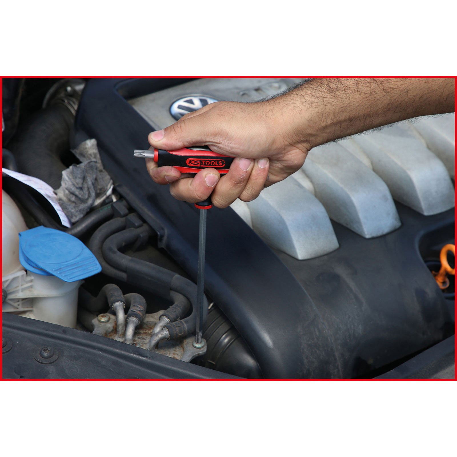 La mano de una persona usando un destornillador en un motor. El motor está en el fondo.
