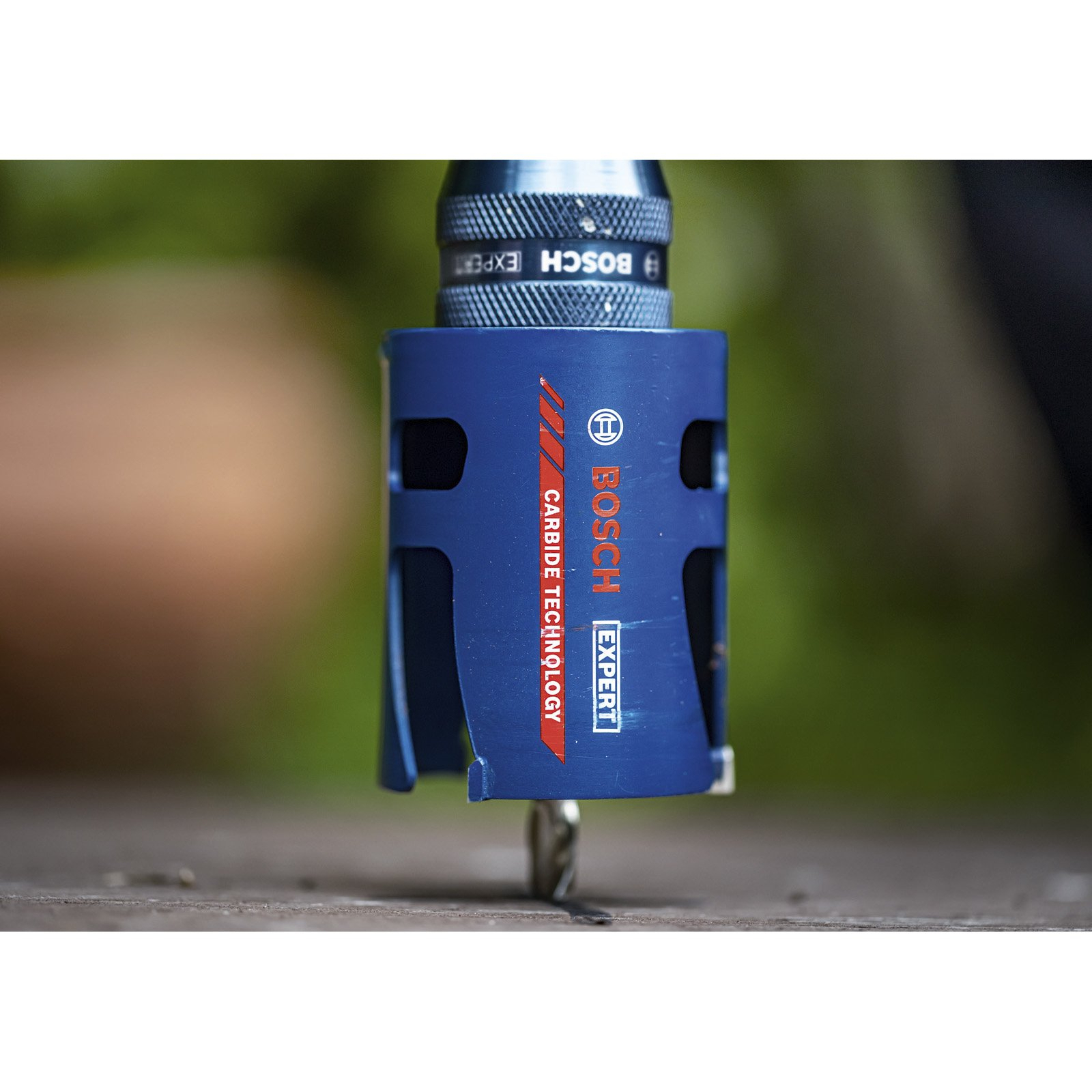 Eine blaue Bosch Expert Hartmetall-Lochsäge bohrt in Holz. Der Bohrer ist an einem Bohrer befestigt.