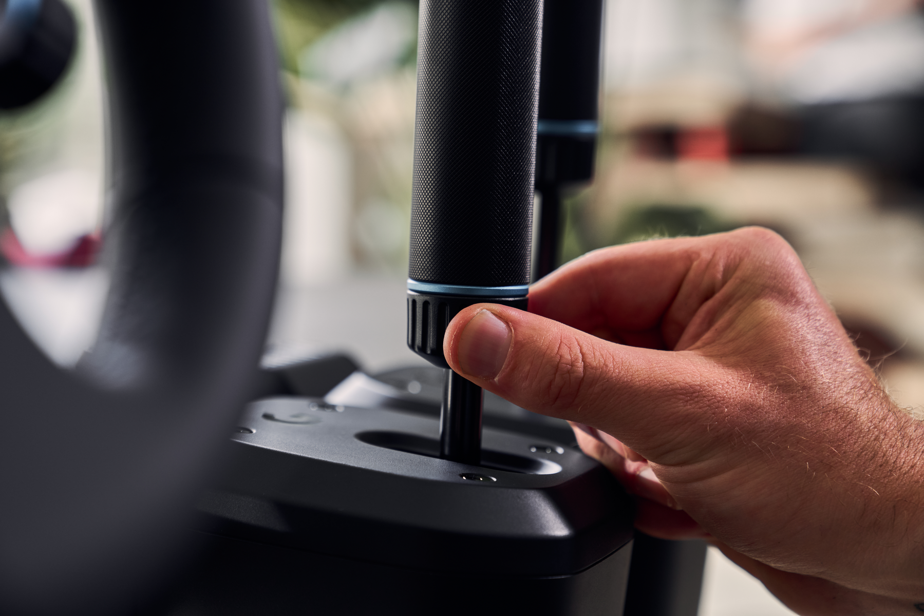Una mano che tiene un joystick. Il joystick fa parte di un dispositivo di gioco nero.