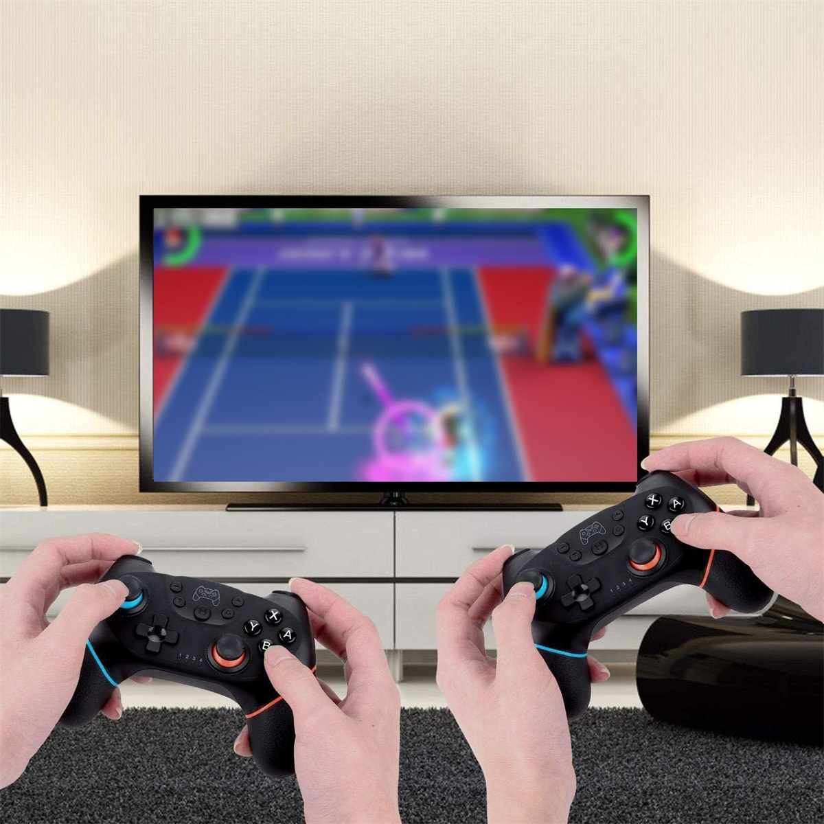Zwei Personen halten schwarze Gamecontroller vor einem Fernseher. Die Controller haben blaue und orangefarbene Knöpfe.