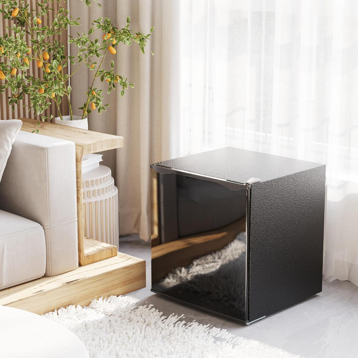 Das Bild zeigt einen Mini-Kühlschrank in einem Wohnzimmer neben einer Couch, einem Tisch und einer Pflanze.