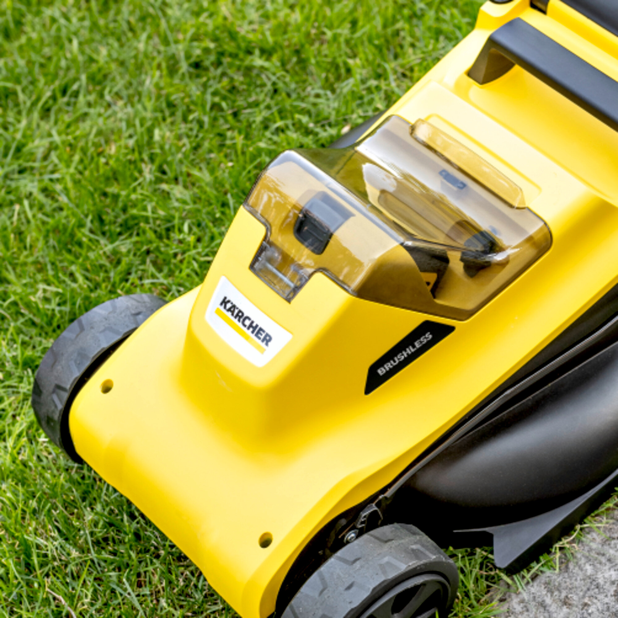 Zbliżenie na żółto-czarną kosiarkę na zielonej trawie. Widoczna jest nazwa marki „Karcher”.