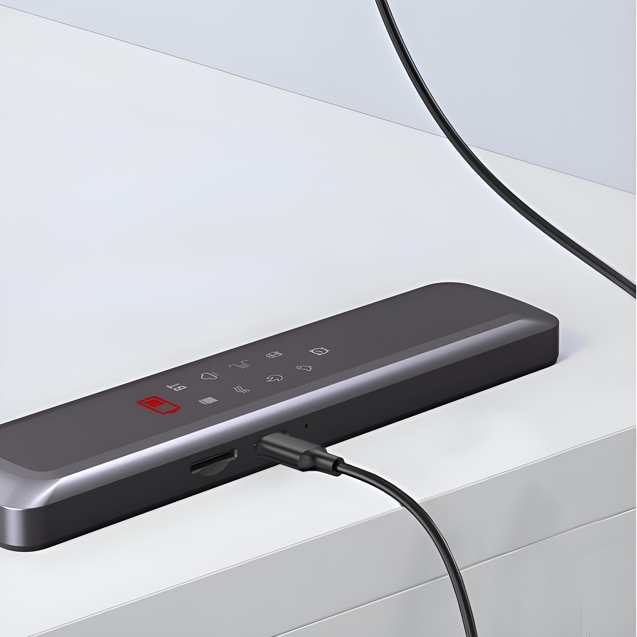 Ein schwarzes Gerät, das an einen USB-Anschluss angeschlossen ist. Es befindet sich auf weißer Oberfläche.