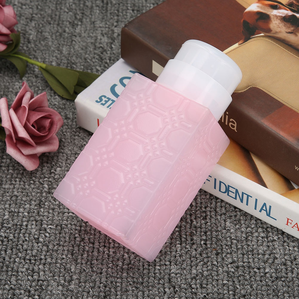 Rosa Flasche mit weißem Deckel auf Büchern und einer Rose. Die Oberfläche ist reflektierend.