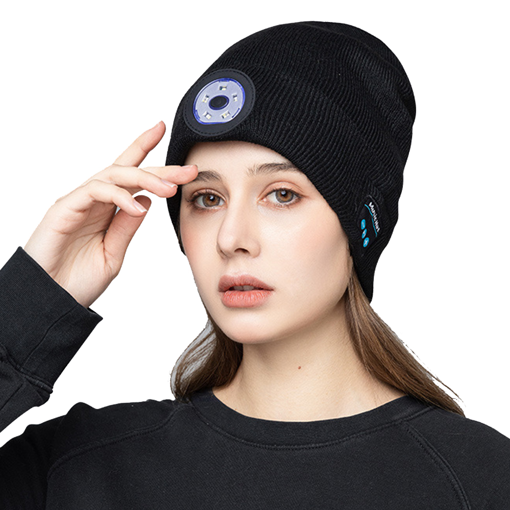 Eine Frau trägt eine schwarze Mütze mit Licht und Bluetooth-Tasten. Sie berührt ihren Kopf.