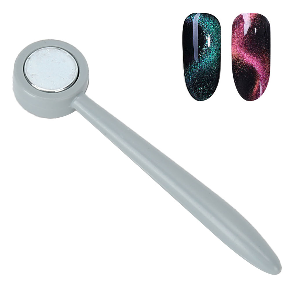 Ein graues Nail-Art-Werkzeug mit rundem Kopf neben zwei Nagelmustern mit Katzenaugeneffekt.
