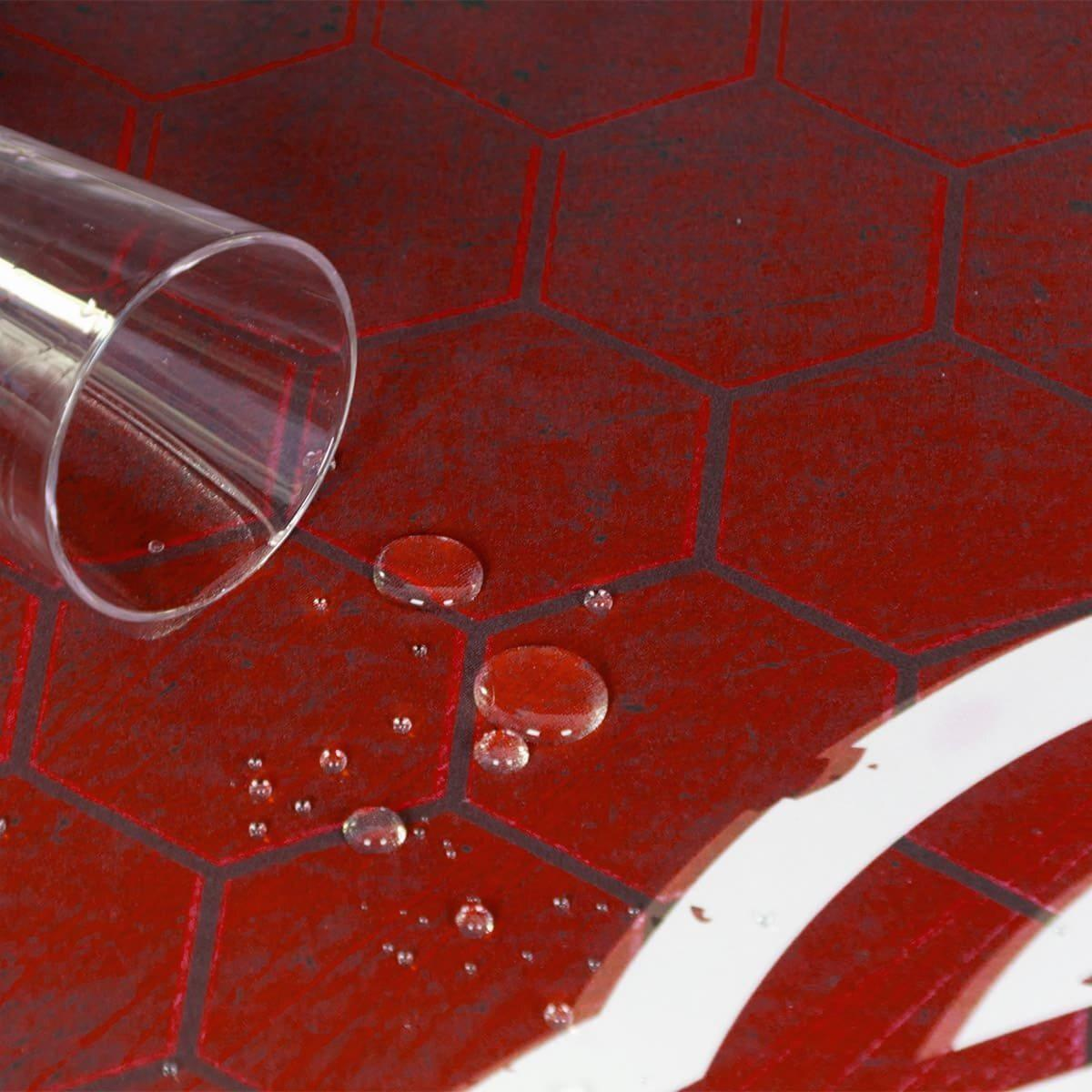 Wassertropfen auf einer roten, sechseckig gemusterten Oberfläche mit einem durchsichtigen Glaszylinder in der Ecke.