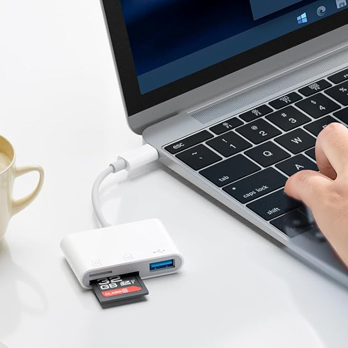 Un laptop con un lettore di schede collegato. Una scheda SD è inserita nel lettore di schede.