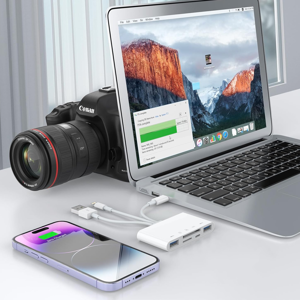 Laptop, telefono, fotocamera e un hub dati collegati, con un telefono in carica.