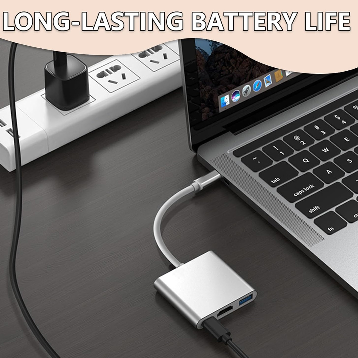 Un hub USB-C argentato è collegato a un laptop e a un caricabatterie su una superficie di legno scuro.