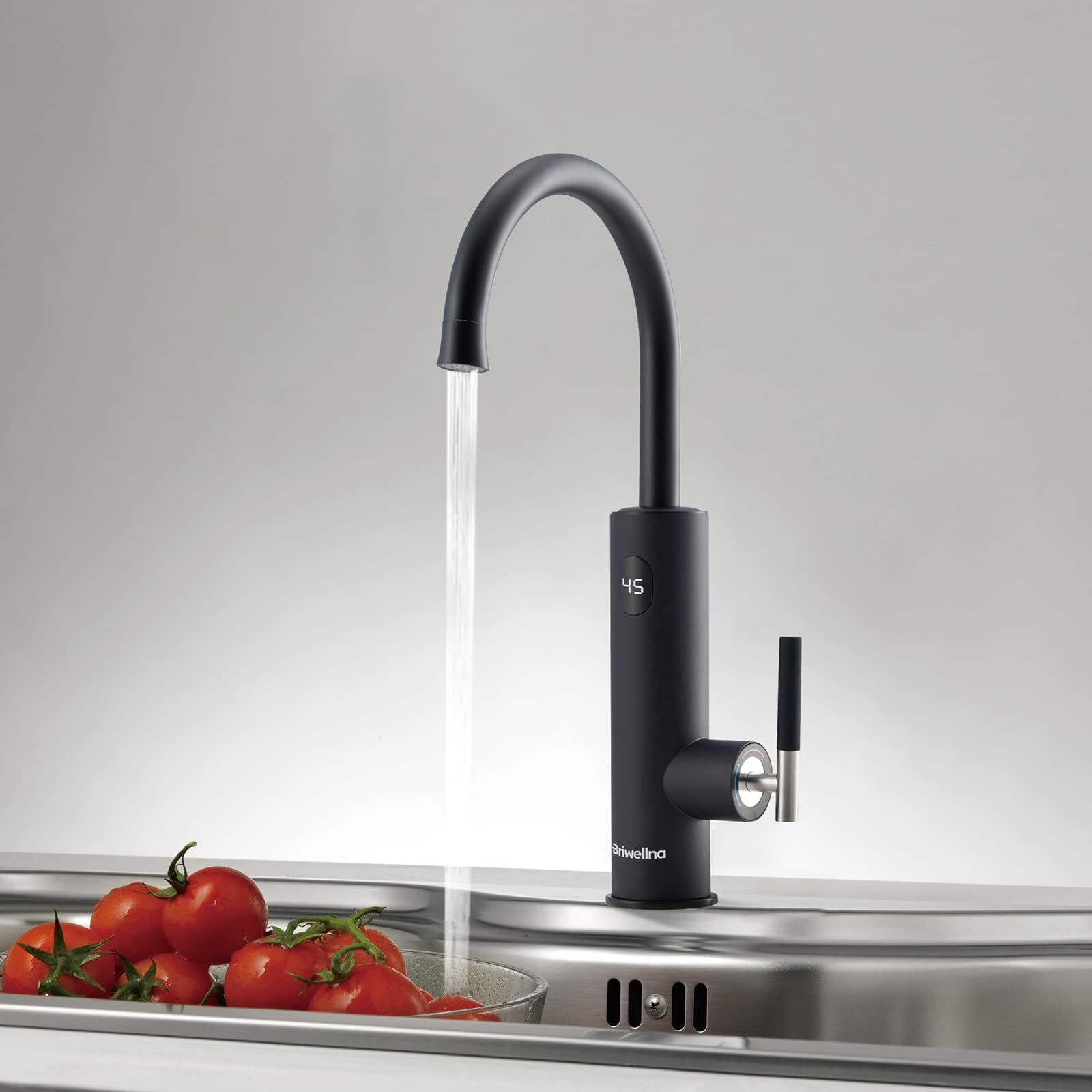 Ein schwarzer Wasserhahn mit Wasser, das in ein Waschbecken fließt, mit roten Tomaten im Vordergrund.