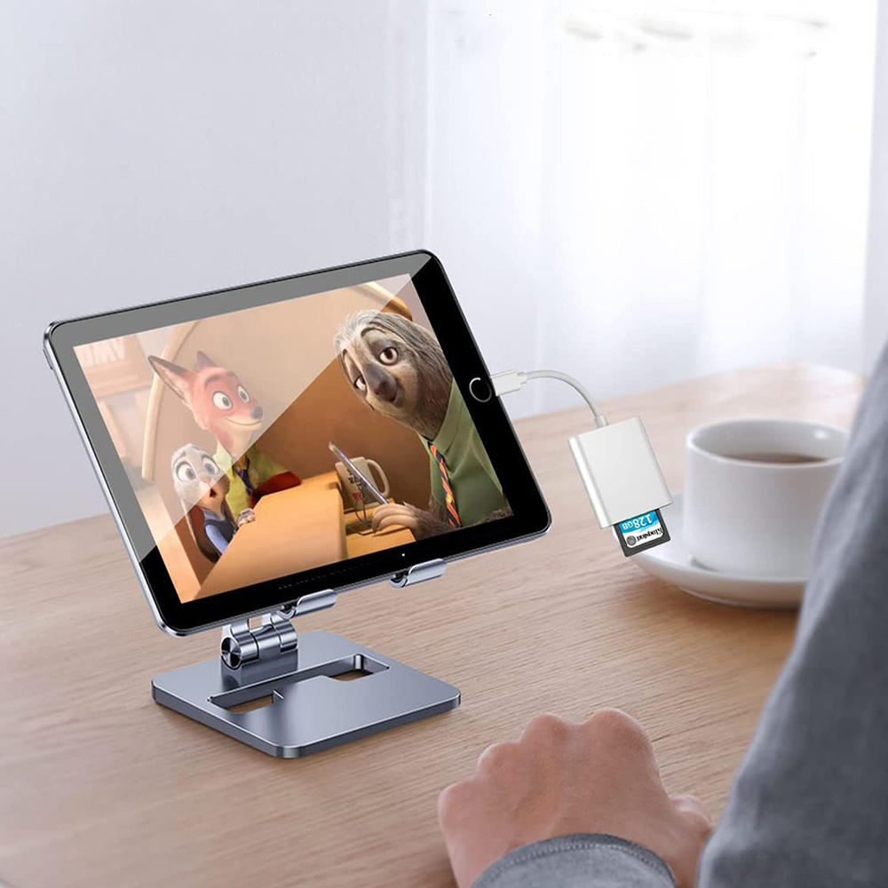 Tablet su supporto, mostra un cartone animato con una volpe e un bradipo. Tazza bianca.
