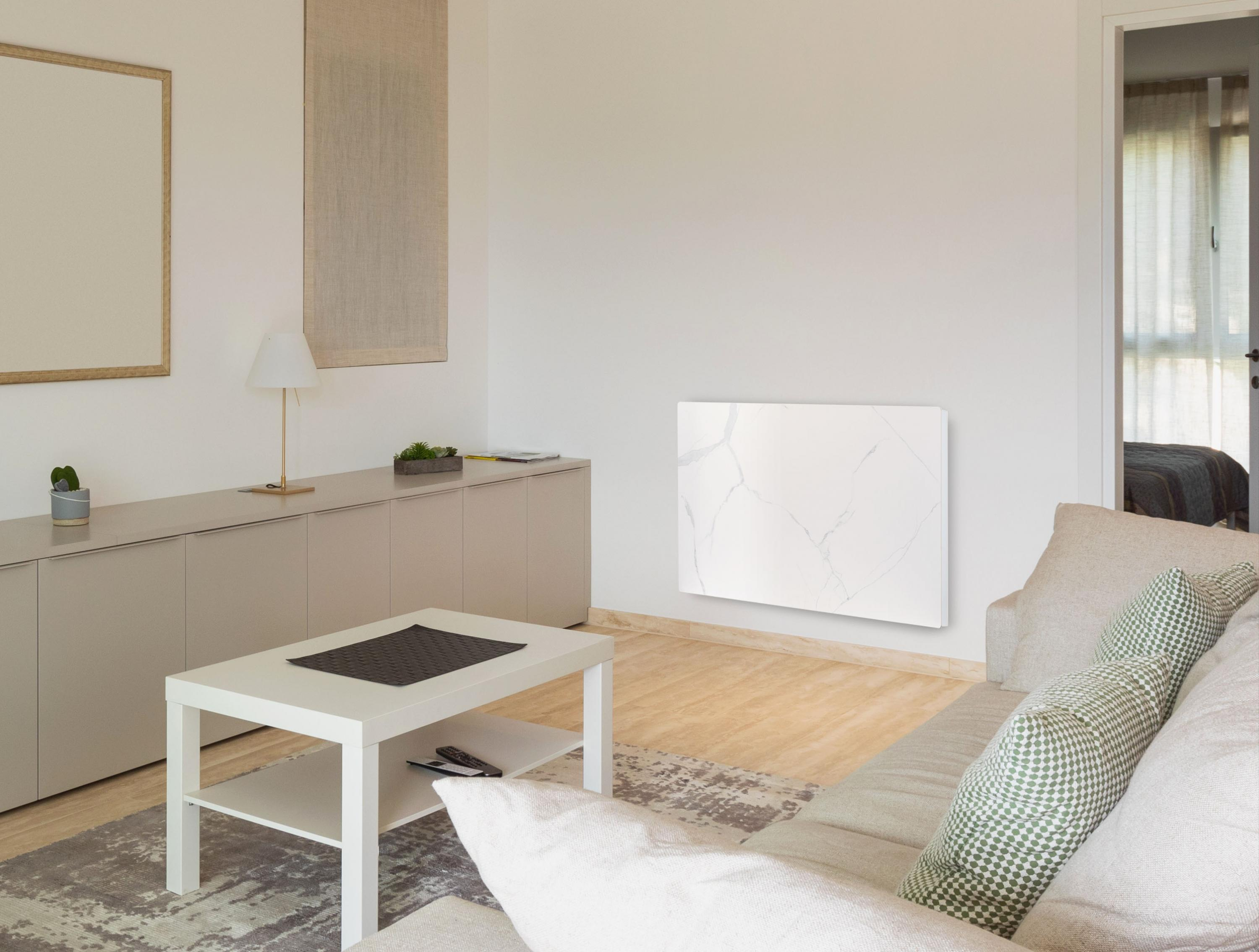 Salón con calefactor blanco montado en la pared. Sofá con almohadas, mesa de centro y obras de arte en la pared.