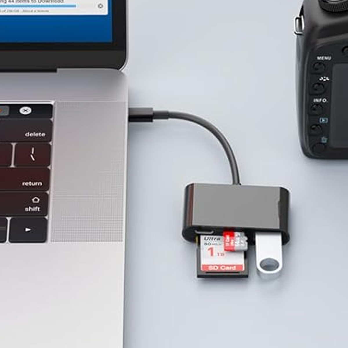 Un laptop con un hub USB-C collegato e una fotocamera. Una scheda SD e un'unità USB sono collegati all'hub.