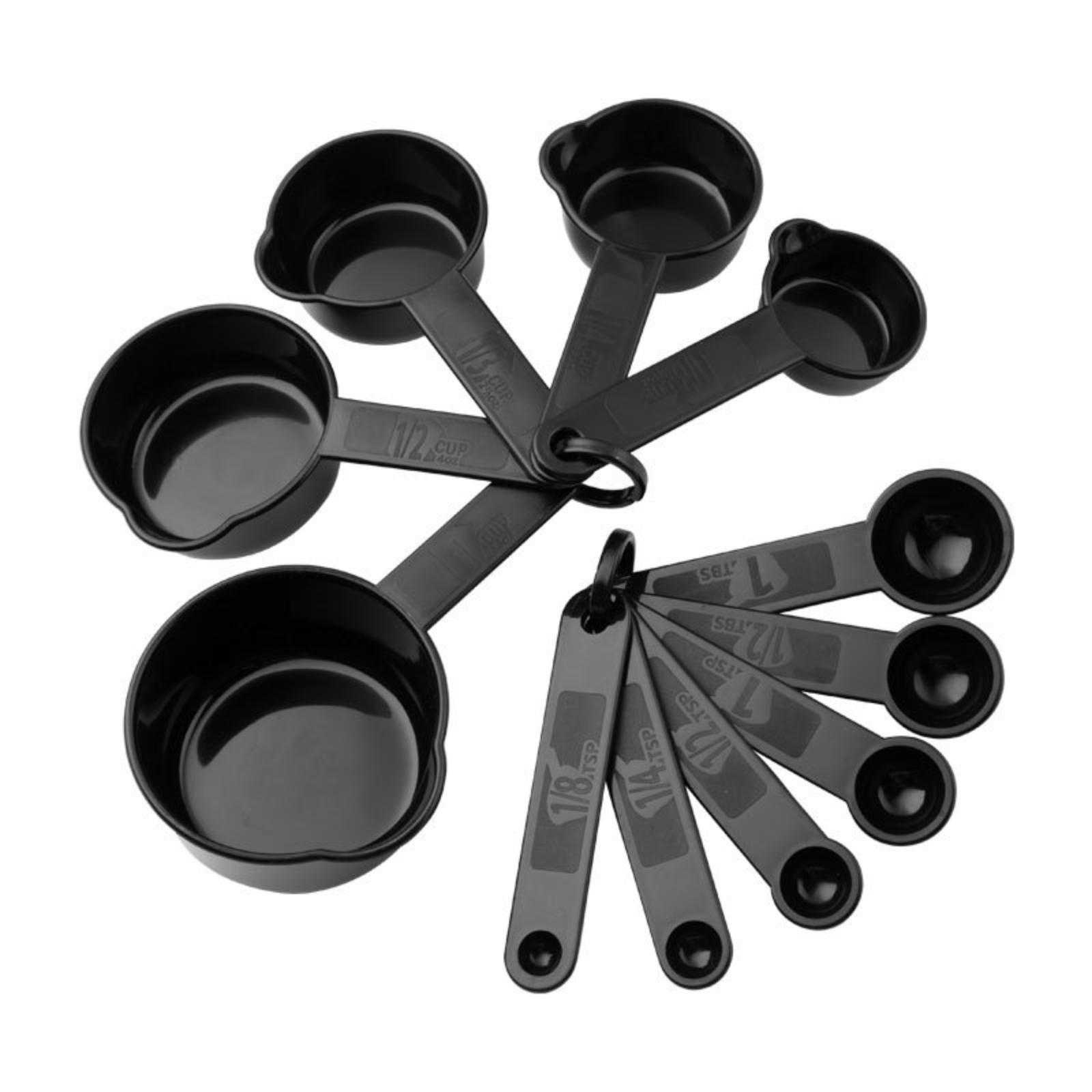 Schwarze Messbecher und -löffel, fächerförmig angeordnet, auf weißer Oberfläche. Verschiedene Größen sichtbar.