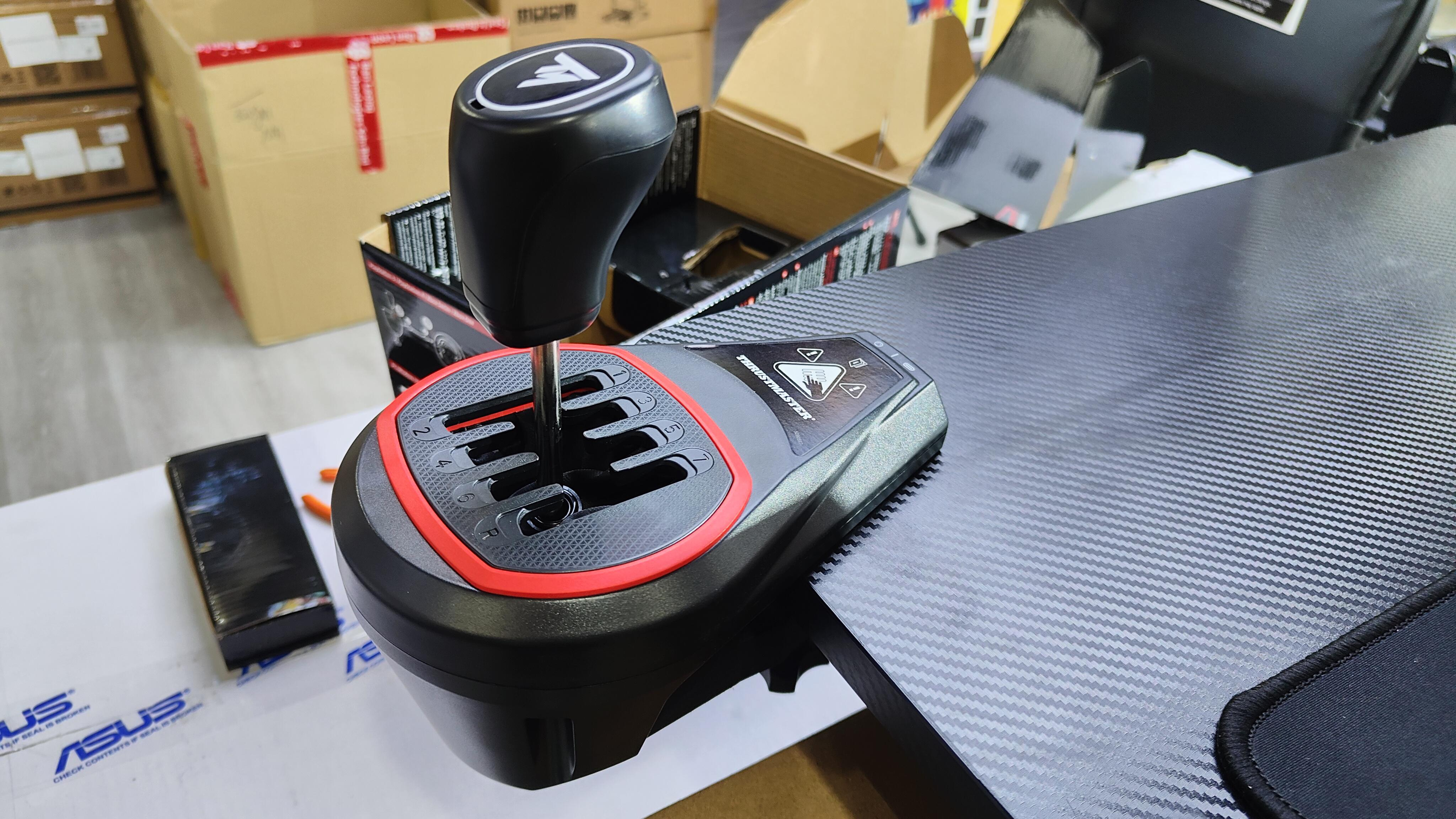 Schwarzer Schalthebel auf einem Schreibtisch. Der Schalthebel ist mit einem Rennsimulator verbunden.